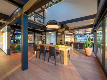 Helles Esszimmer mit Holztablett, Stühlen und Küchenbereich.