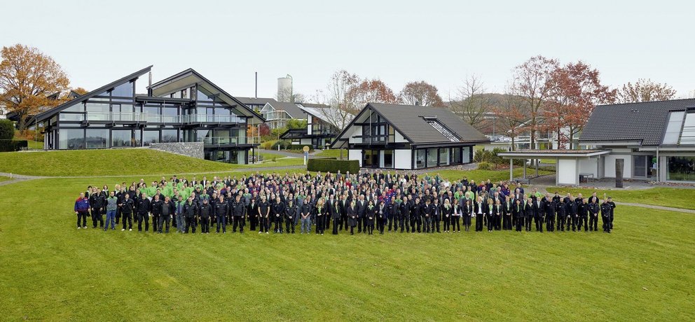 Gruppenfoto vor modernen Gebäuden im Freien Vielzahl von Menschen versammelt auf einer Wiese vor modernen Architekturen