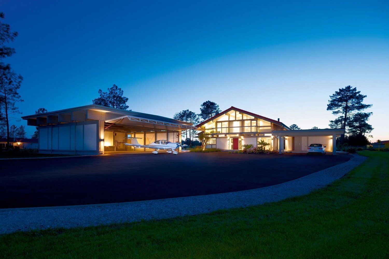 HUF Haus mit integriertem Flugzeughangar und sanfter Beleuchtung