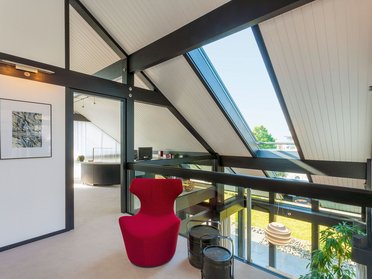HUF Musterhaus Koblenz ebenholz 5 Stylish interior featuring a red chair and large windows