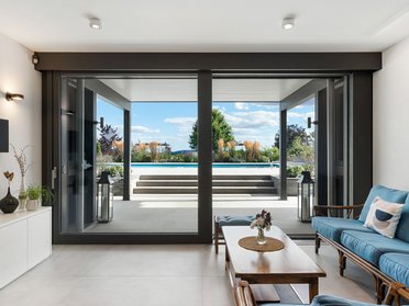 Helles Wohnzimmer mit großen Fenstern und Zugang zur Terrasse