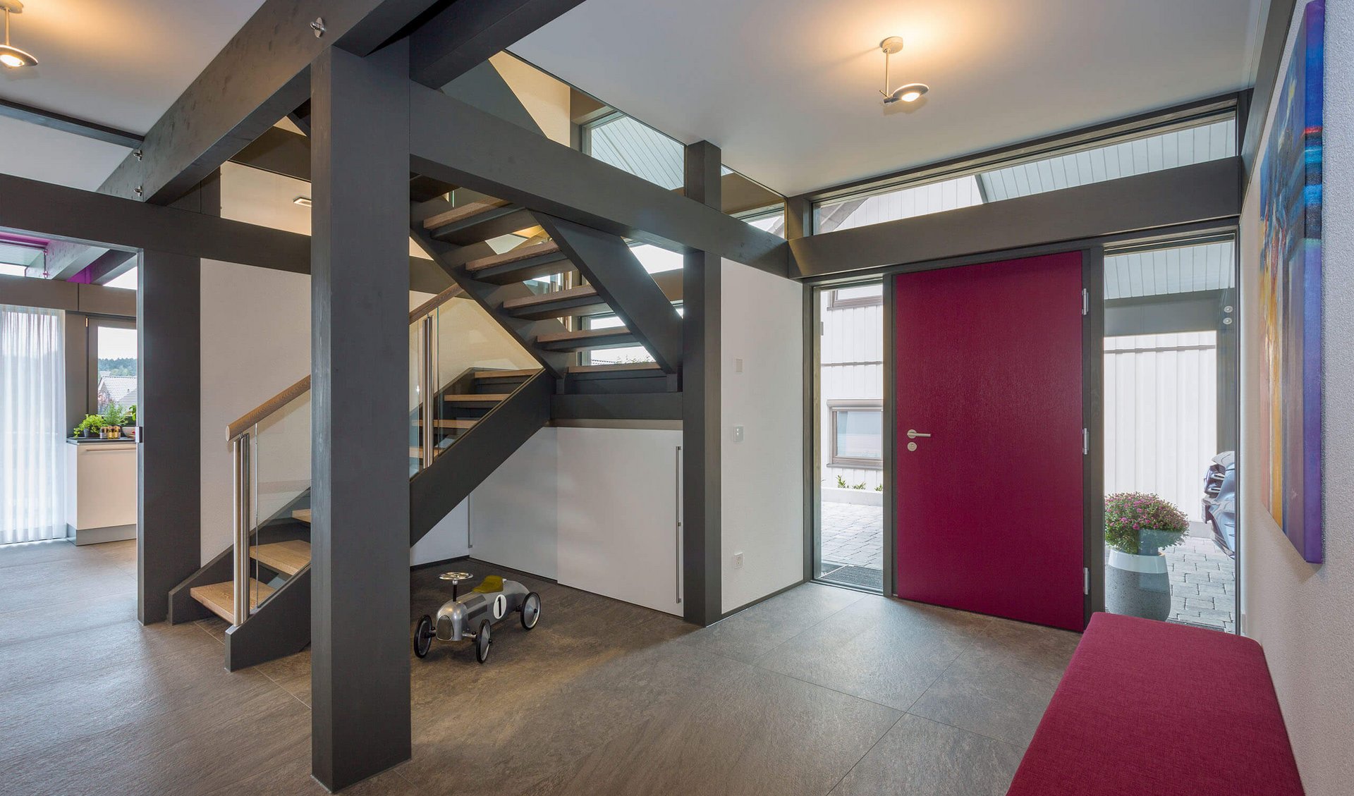 Ein heller Flur mit moderner Treppe und roter Eingangstür