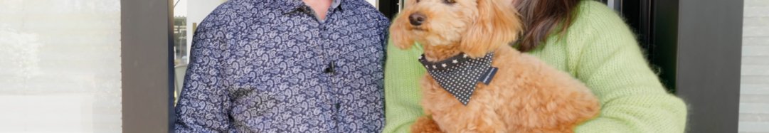 Familie Müller im HUF Haus_Bestandsgebäude_Erfahrungen Ein Mann und eine Frau stehen vor einer Eingangstür mit einem Hund.