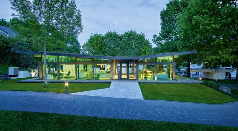 Moderne Architektur eines Hauses umgeben von Bäumen Haus mit großen Fenstern und einem grünen Garten im Hintergrund