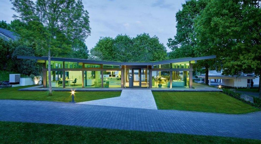 Haus mit großen Fenstern und einem grünen Garten im Hintergrund