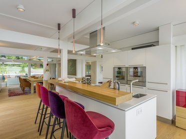 Helle, moderne Kücheneinrichtung mit Barhockern und Blick in den Garten