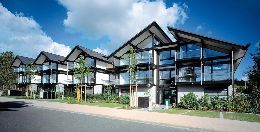 Reihenhaus mit modernen Linien, großen Fenstern und grüner Umgebung