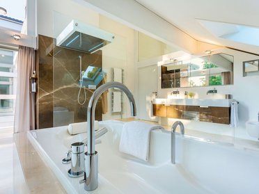 Helles Badezimmer mit Badewanne, Dusche und Spiegeln in stilvollem Design