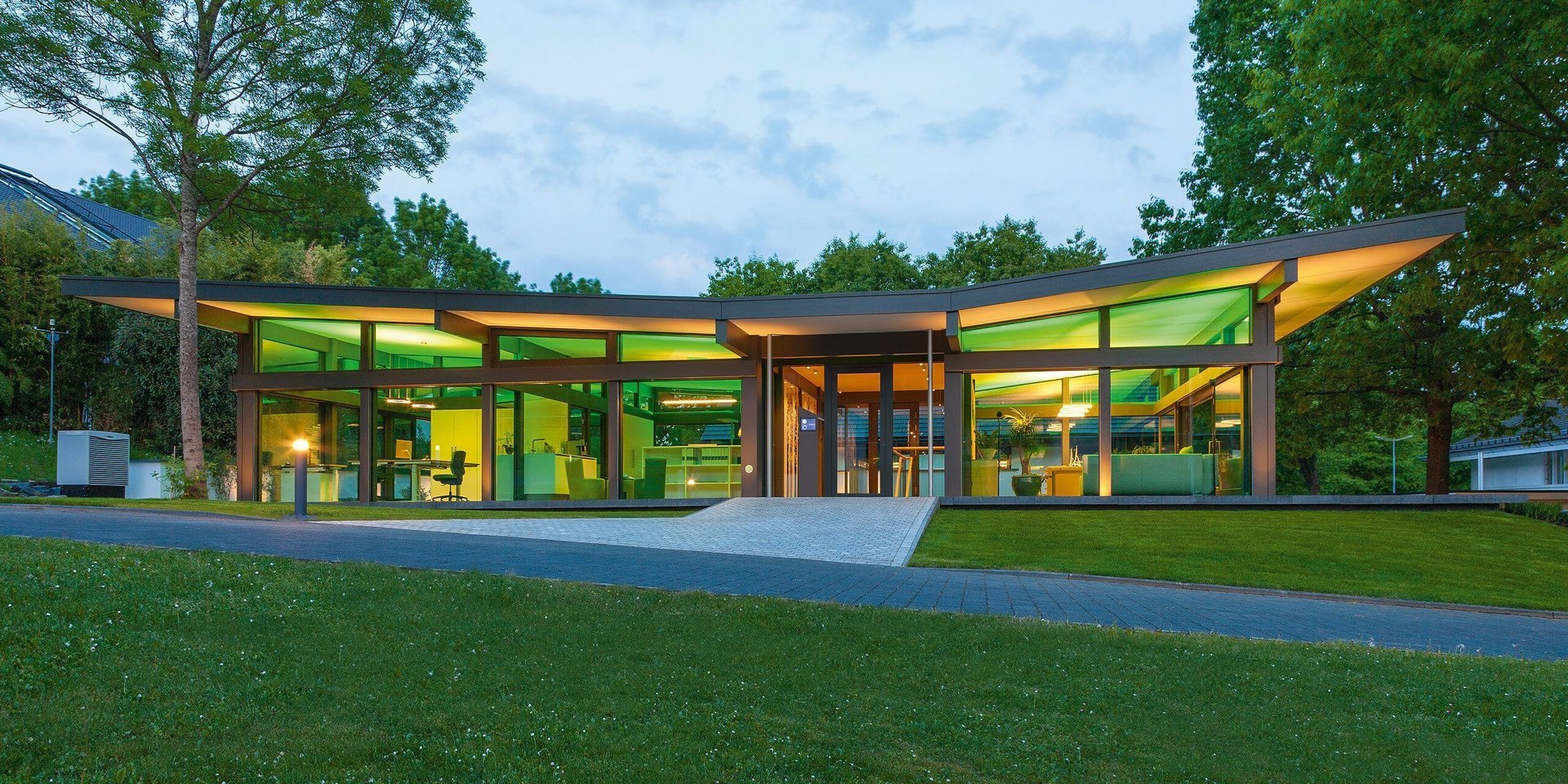Zeitgenössisches Gebäude mit großen Fenstern und Gartenlandschaft