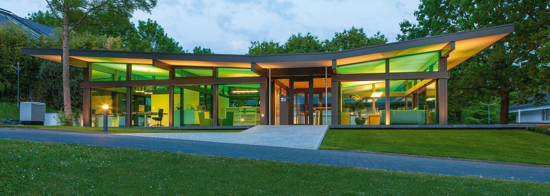 Zeitgenössisches Gebäude mit großen Fenstern und Gartenlandschaft