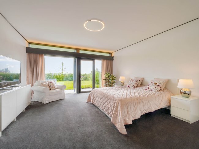 Helles Schlafzimmer mit großen Fenstern und Pflanzen im HUF HAUS