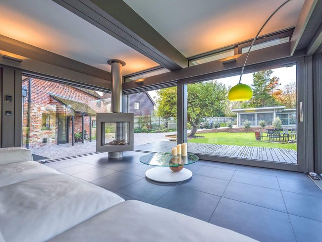 Stylischer HUF Anbau erweitert Wohnraum harmonisch Moderne Architektur mit Kamin und Blick ins Grüne