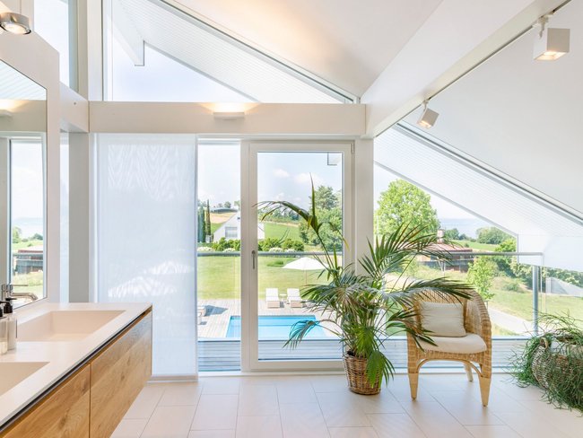 Helles Badezimmer mit Ausblick auf den Garten und Pool