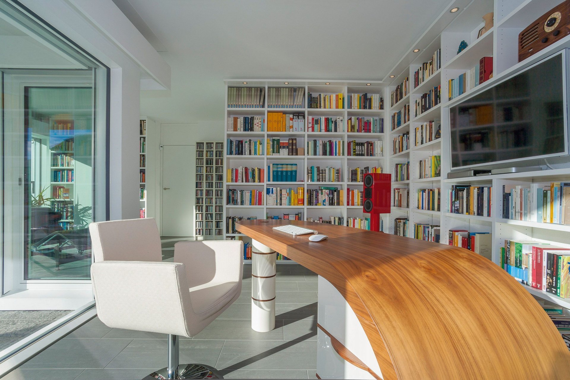 Modernes Arbeitszimmer mit Bücherregalen Ein stilvolles Arbeitszimmer mit einem Holzschreibtisch und bunten Bücherregalen