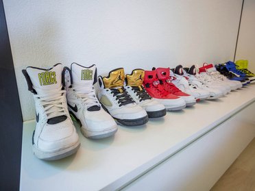 Vielfalt an Sportschuhen auf einem weißen Regal in einem modernen Raum