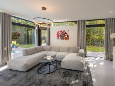 Lichtdurchflutetes Architektenhaus mit modernem Design Helles Wohnzimmer mit großzügiger Fensterfront und moderner Einrichtung