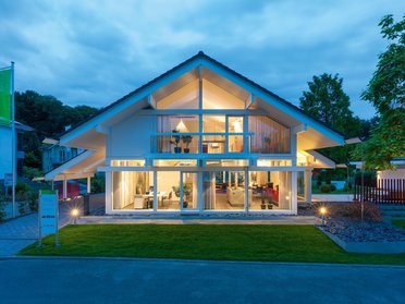 Helles, modernes Haus mit großen Fenstern in der Dämmerung