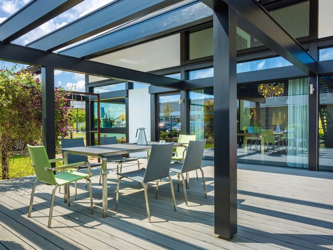 Gemütliche Terrasse mit sechs Stühlen und Tisch, umgeben von Pflanzen