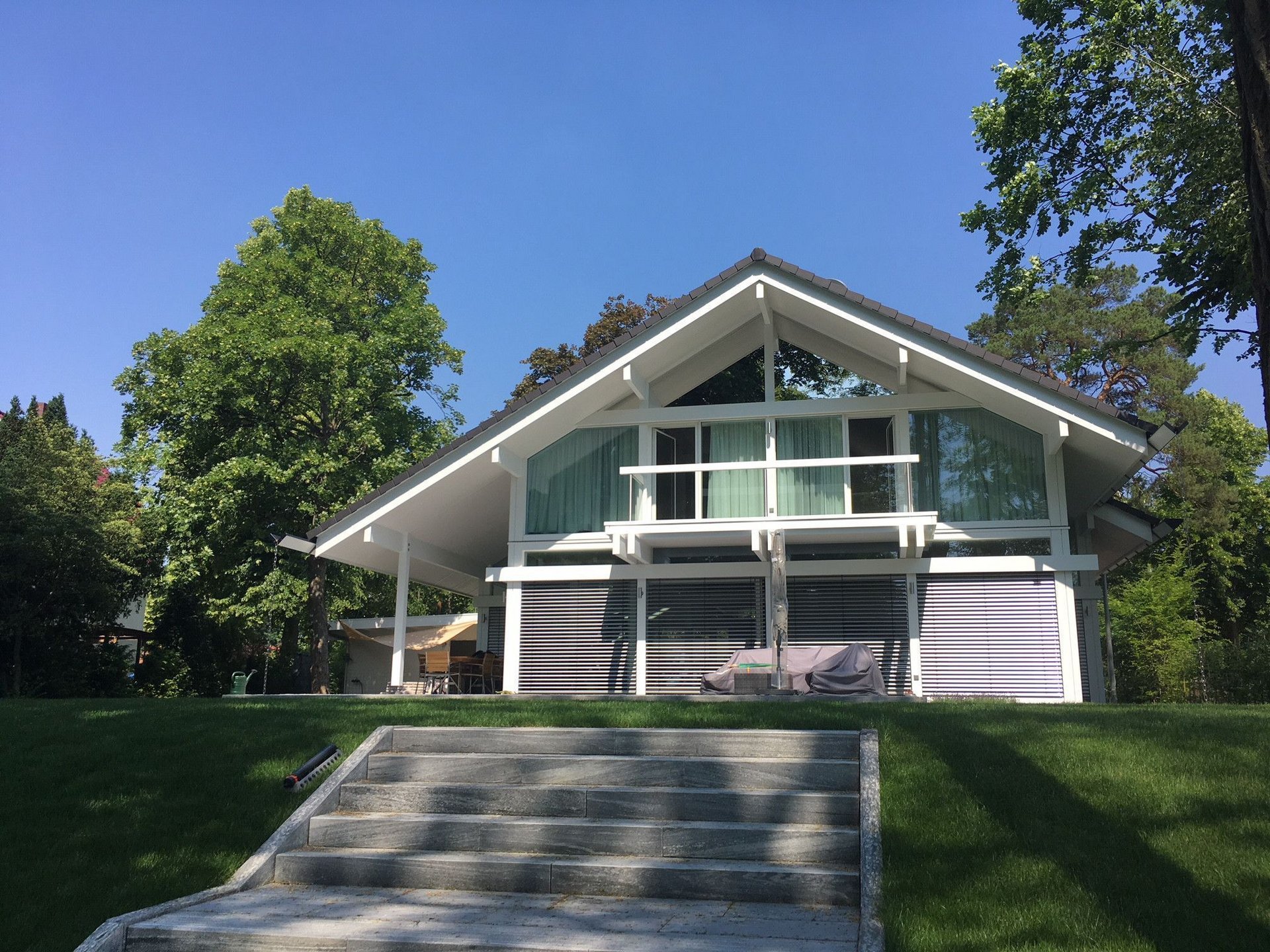 Moderne Architektur eines Einfamilienhauses Haus mit großem Garten und moderner Glasfront unter blauem Himmel