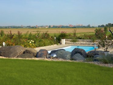 Fachwerkhaus HUF HAUS ART 4 mit Gartenansicht Ansicht eines Fachwerkhauses mit Pool und Landschaft im Hintergrund