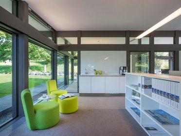 Moderne Büroumgebung mit Sitzgelegenheiten Heller Büroraum mit grünen Stühlen und großen Fenstern