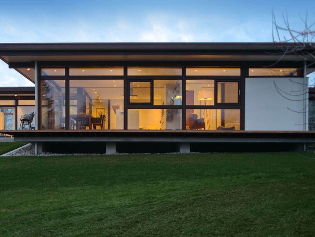 Moderner Bungalow mit großen Fenstern und Garten Architektenhaus im Grünen mit klaren Linien und großzügigen Glasflächen