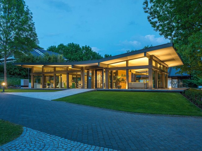 Moderne Architektur bei Nacht mit lebendigem Ambiente Ein elegantes Gebäude mit großzügigen Glasflächen und eingerichteten Gärten