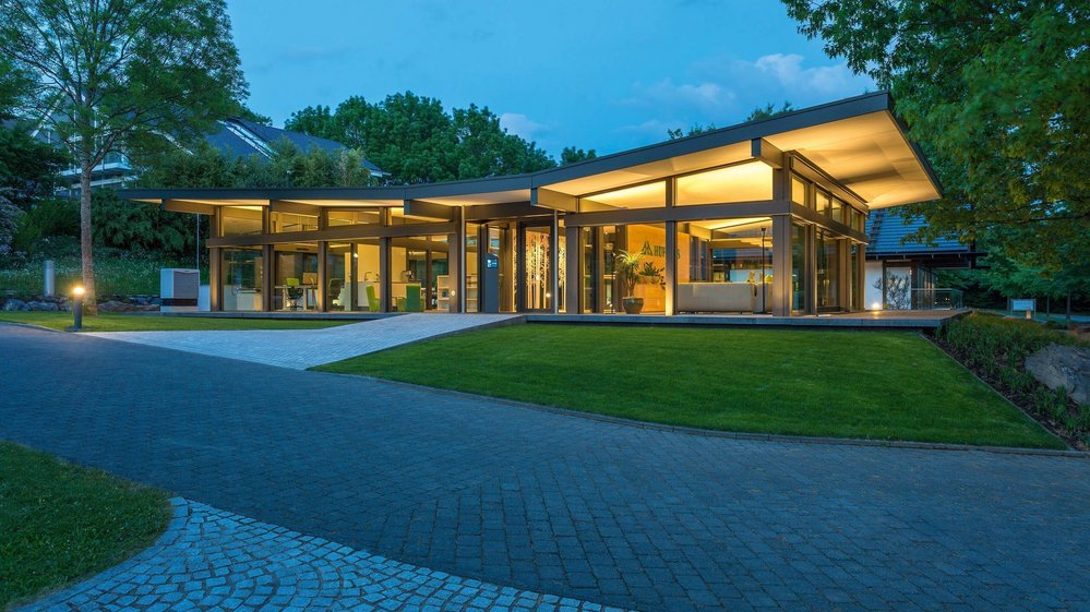 Moderne Architektur bei Nacht mit lebendigem Ambiente Ein elegantes Gebäude mit großzügigen Glasflächen und eingerichteten Gärten