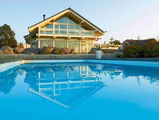 Fachwerkhaus HUF HAUS ART 4 mit Pool Moderne Architektur eines HUF HAUS mit einem blauen Pool im Vordergrund