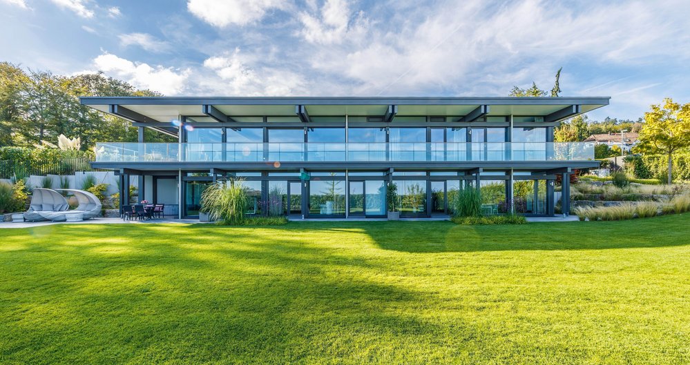 Maximale Transparenz im HUF HAUS mit Flachdach Moderne Architektur des HUF HAUS mit großzügigen Glasfronten und grünem Garten