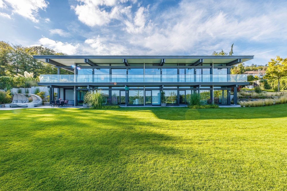 Moderne Architektur des HUF HAUS mit großzügigen Glasfronten und grünem Garten