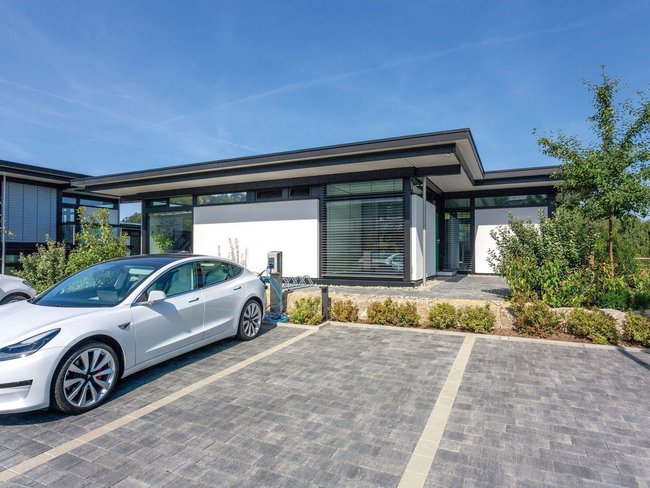 Bürogebäude mit moderner Architektur und Elektroauto in der Einfahrt