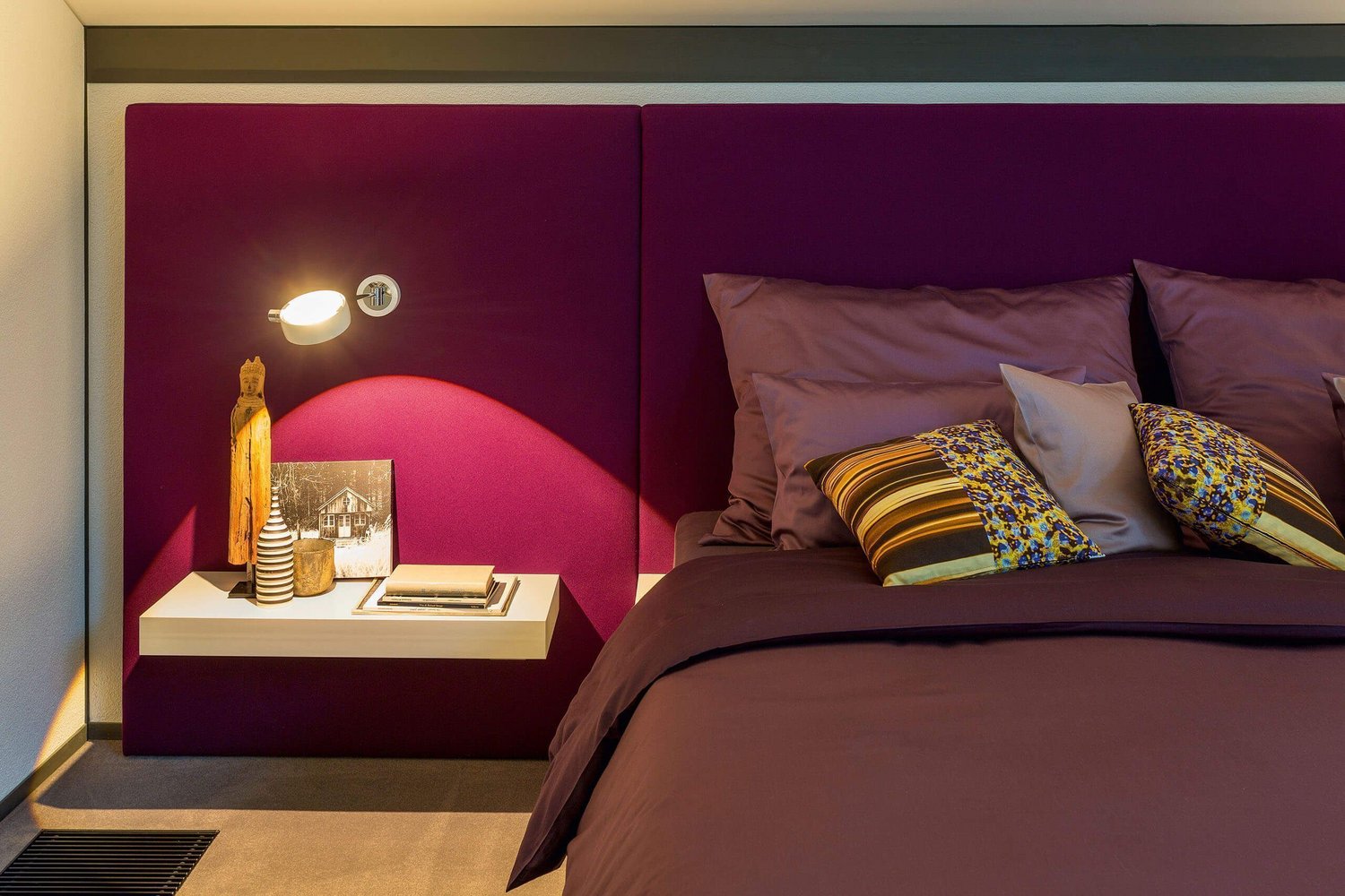 Stilvolles Schlafzimmer mit dekorativen Kissen und Nachttisch