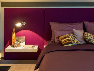 Stilvolles Schlafzimmer mit dekorativen Kissen und Nachttisch