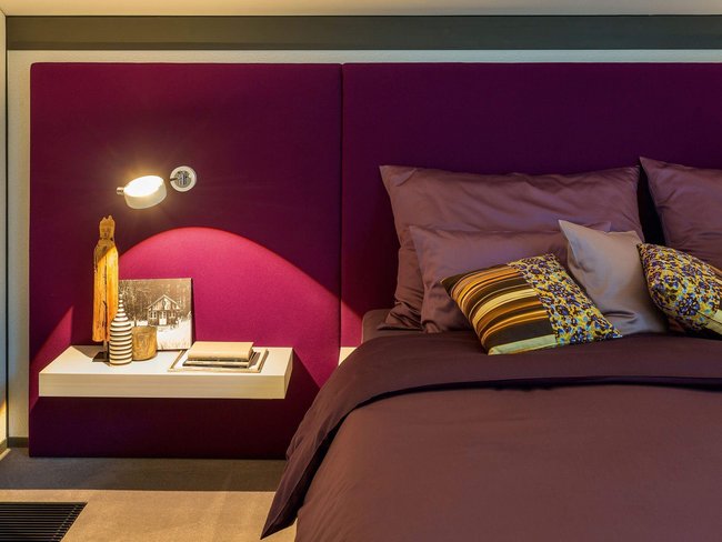 Stilvolles Schlafzimmer mit dekorativen Kissen und Nachttisch