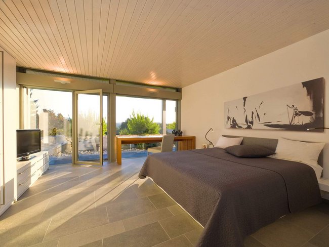 Exklusive Schlafzimmeransicht eines HUF HAUS Modernes Schlafzimmer mit großen Glasflächen und eleganter Ausstattung