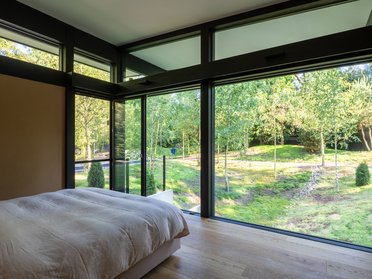Moderner HUF Bungalow mit großen Fenstern Einladendes Schlafzimmer in einem modernen Bungalow mit Aussicht auf die Natur