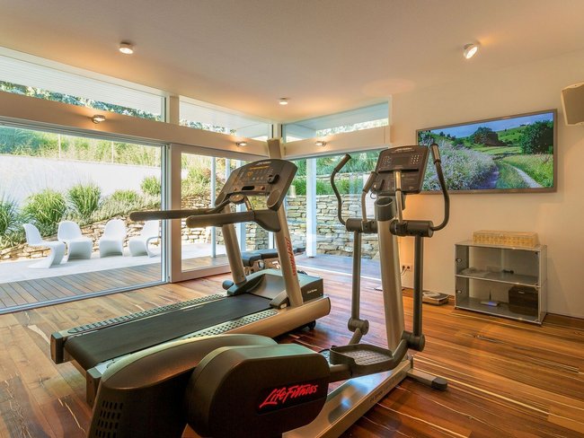 Fitnessgeräte in einem hellen Raum mit großem Fenster zur Terrasse