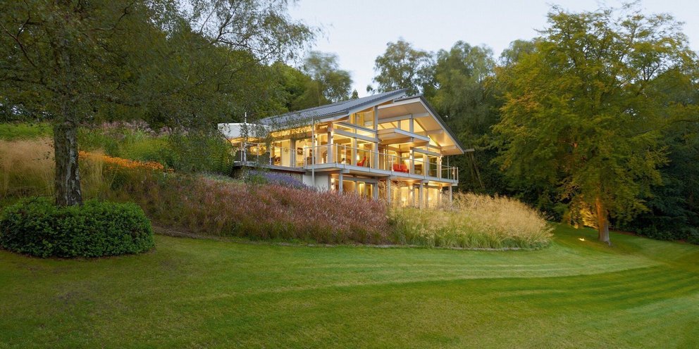 Ein modernes Haus umgeben von grasbewachsenen Hängen und Bäumen