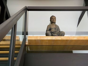 Innenansicht eines Architektenhauses mit Buddha-Skulptur und Holzdetails