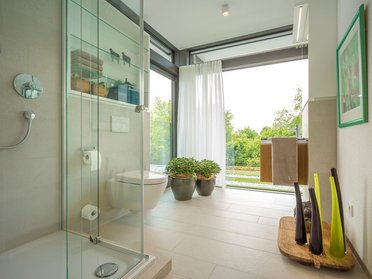 Moderne Badezimmeransicht mit Blick ins Grüne Helles Badezimmer mit Dusche, Pflanzen und natürlichem Licht