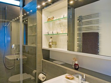 Helles Badezimmer mit Glasdusche, modernen Armaturen und Regalen