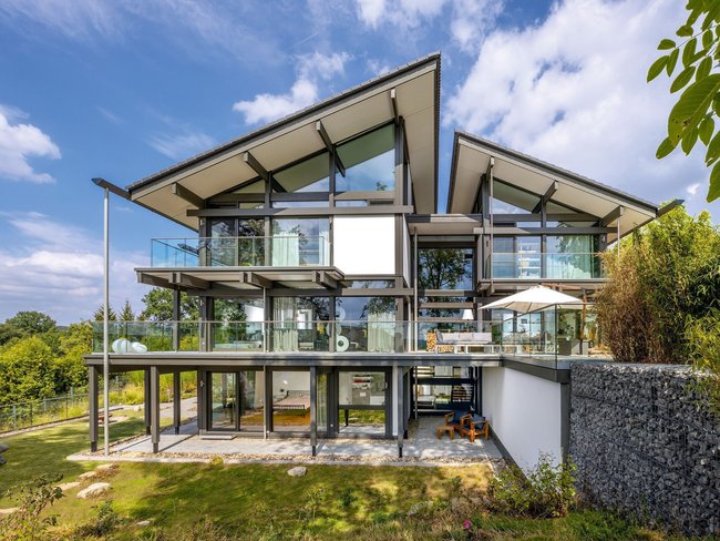 Architektenhaus mit großzügigen Fenstern und Balkonen in der Natur