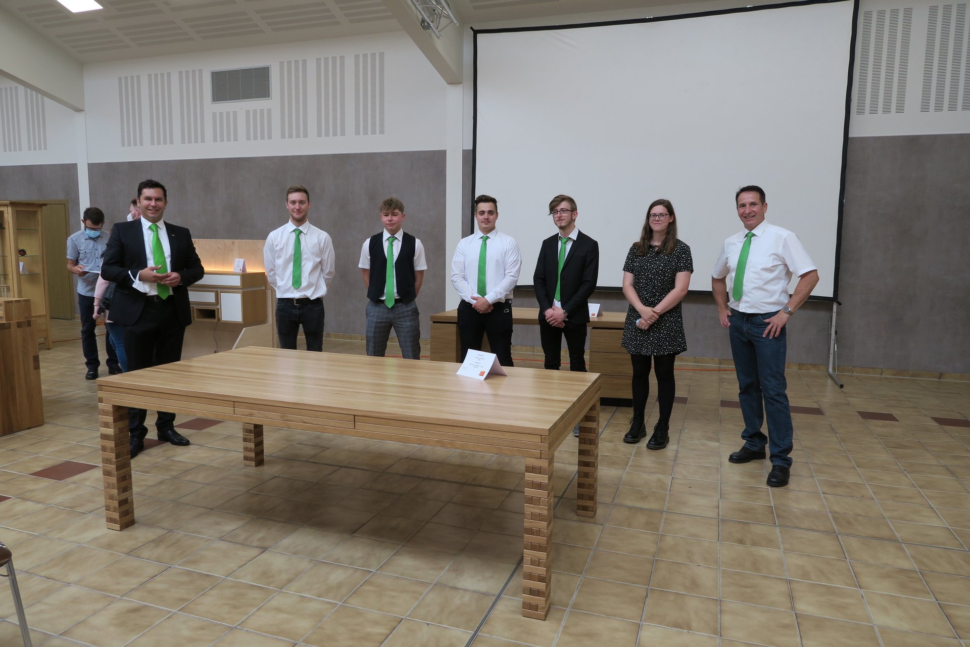 Jubiläumskalender 110 Jahre HUF HAUS Veranstaltung Menschen in Anzug und Krawatte stehen vor einem Tisch während einer Jubiläumsfeier