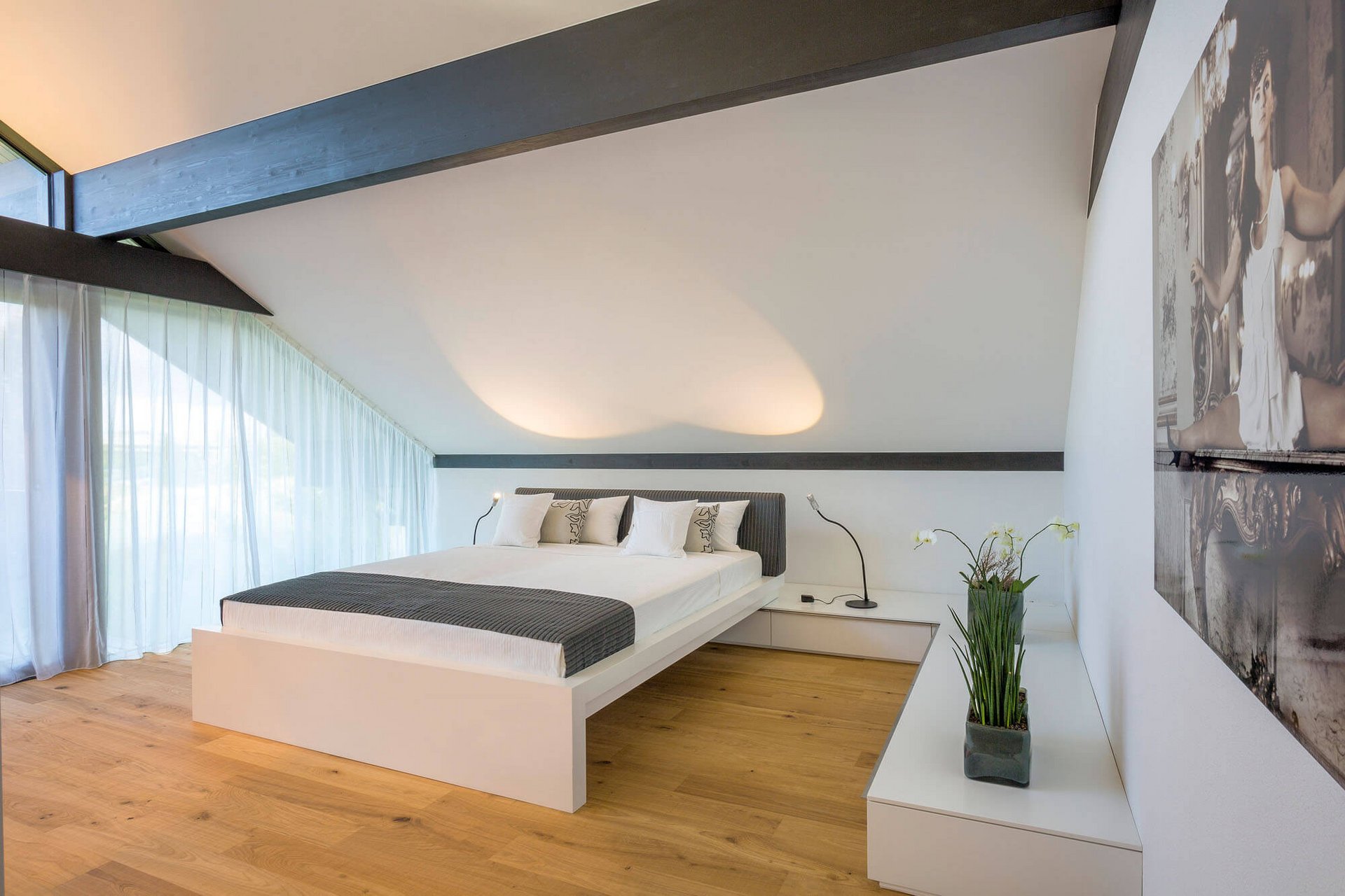 Modernes Schlafzimmer mit großem Bett und Holzfußboden Helles Schlafzimmer mit großer Fensterfront und minimalistischer Einrichtung