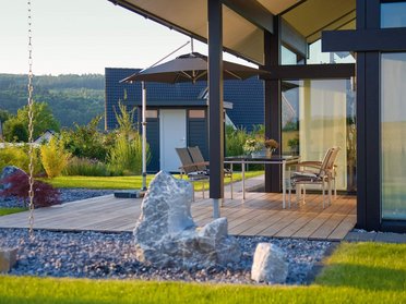 Terrasse eines Architektenhauses mit Garten und Steinen