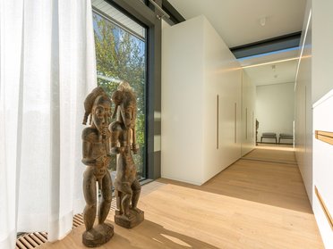 Bright hallway featuring decorative wooden sculptures and large windows