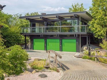 Modernes HUF Haus mit grünen Garagentoren und Bürogebäude