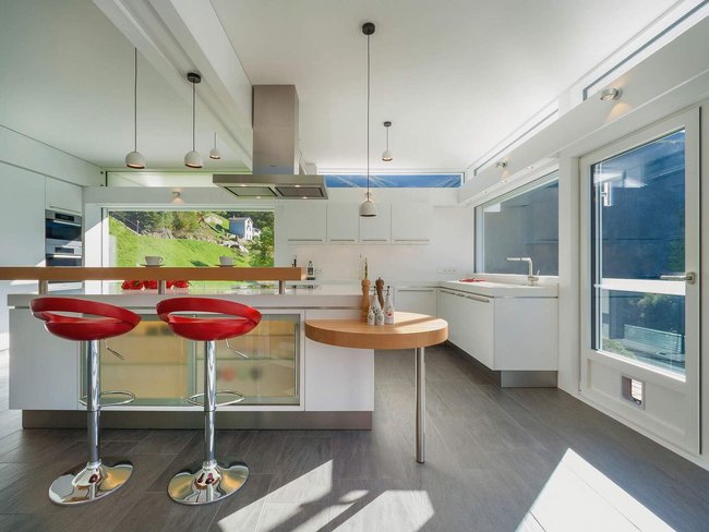 Moderne Küche eines HUF Haus ART 3 in Hanglage Helle, moderne Küche mit roten Barhockern und großflächigen Fenstern