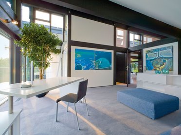 Ein luftiger Raum mit Kunst und Pflanzen, große Fenster und stilvolles Mobiliar
